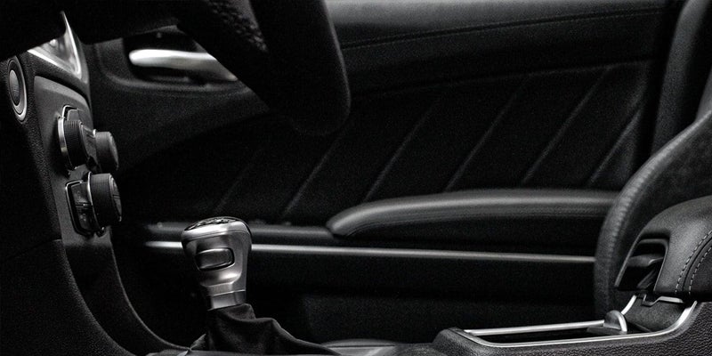 Manual gear shifter in a black car interior