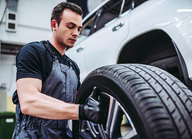 A technition holding tire in hand while repairing